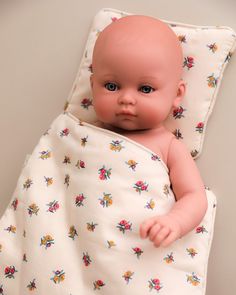 a baby doll wrapped in a blanket laying on top of a bed next to a wall