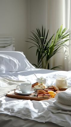 a tray with food on top of a bed next to a cup and saucer