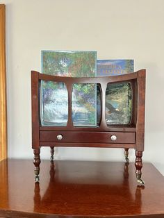 a wooden table with two televisions on top of it and some paintings in the background