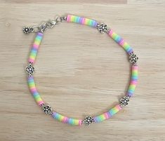 a multicolored beaded bracelet on a wooden surface with silver beads and flowers