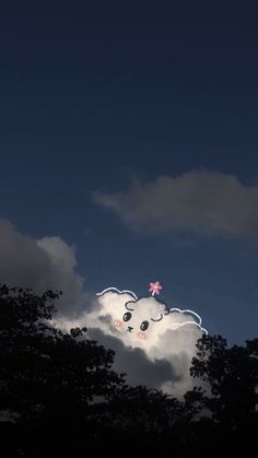 there is a kite flying in the sky with clouds behind it and some trees below