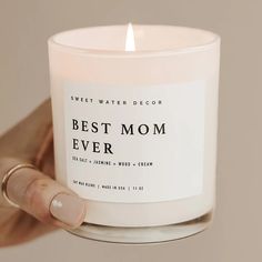 a person holding a candle with the words best mom ever written on it in front of them