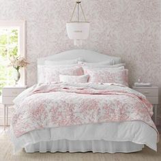 a bedroom with pink and white wallpaper and bedding