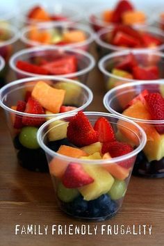 small plastic cups filled with fruit on top of a wooden table