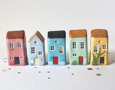 a row of small houses sitting next to each other on top of a white surface