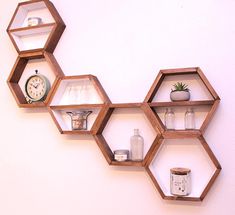 three hexagonal shelves on the wall with various items in them and an alarm clock