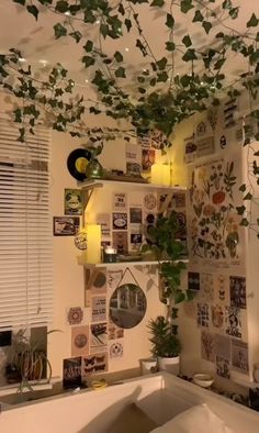 a living room filled with lots of plants and pictures hanging from the ceiling next to a window