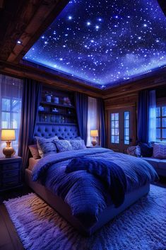 a bed room with a large bed covered in blue blankets and stars on the ceiling