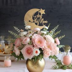 a vase filled with pink and white flowers on top of a table next to candles