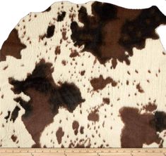 a brown and white cow print rug with a ruler in front of the area where it is