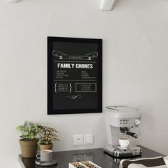 a black and white poster on the wall above a table with two coffee cups, an espresso machine and a potted plant