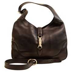 A Gucci Jackie made of black leather with light gold toned hardware. The interior is lined with beige fabric, and next to the major compartment it features three side pockets of which one has a zipper. The bag can be closed with the piston closure. The bag can be worn as a shoulder strap with the short strap (max. 48 cm), or as a crossbody bag with the additional strap (total max. ca. 100 cm). The bag will be delivered with cards, and without the dust bag. The condition of the bag is very good w Gucci Crossbody Bag Vintage, Gucci Soft Leather Shoulder Bag, Designer Gucci Soft Leather Bag, Designer Gucci Bag In Soft Leather, Gucci Satchel With Branded Hardware, Gucci Shoulder Bag With Branded Hardware For Business, Gucci Luxury Soft Leather Shoulder Bag, Gucci Business Shoulder Bag With Branded Hardware, Luxury Gucci Shoulder Bag In Soft Leather