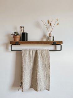 a towel is hanging on a shelf above a potted plant and some other items