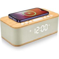 an alarm clock radio with a cell phone on the front and back panel, sitting on top of it