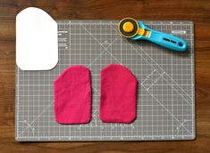 a pair of pink mitts sitting on top of a cutting board