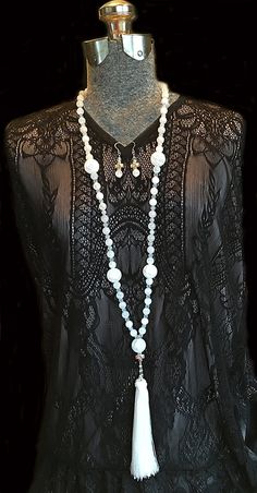 Make a dramatic statement in this stunning long, white frosted glass beaded tassel necklace. The opera length necklace features small silver crosses depicting the Virgin Mary tenderly cradling the baby Jesus. The image appears on both sides of the cross. The six inch tassel is luxurious and suspended from a pearl and silver loop of rosary chain. Beautiful in daylight or candlelight this lovely necklace would be stunning against velvet for a winter bride. The matching earrings also feature fro... White 8mm Beaded Bohemian Necklaces, White Bohemian Necklaces With 8mm Beads, White Gemstone Beads Long Necklace, Elegant White Pearl Rosary, White Beaded Long Necklace For Gift, Spiritual White Cross Jewelry, Elegant Beaded Rosary For Jewelry Making, Elegant White Rosary With Round Beads, White Beaded Lariat Jewelry