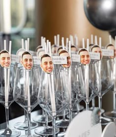 many wine glasses are lined up with pictures of the same man on them and one is empty