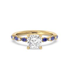 a yellow gold engagement ring with an oval cut diamond and blue sapphire stones on the side