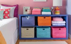 a bedroom with pink walls and colorful baskets on the shelf