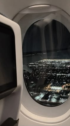 an airplane window looking out at the city lights