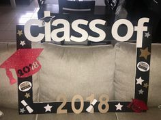 a class of 2018 photo frame with graduation caps and stars on the front, sitting on a couch