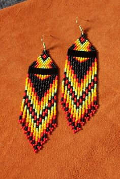 two pairs of beaded earrings sitting on top of a brown cloth covered surface,