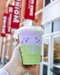 a hand holding up a green and purple starbucks cup