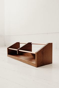 a wooden box with two compartments on the bottom and one in the middle, sitting on a white floor