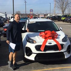 a man standing next to a white car with a red bow on it