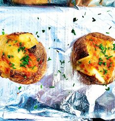 two pieces of bread with cheese and herbs on them sitting on aluminum foil covered baking pans