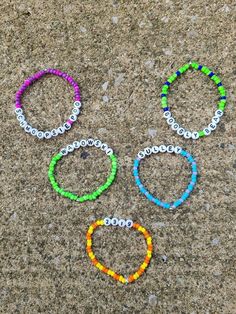 four different colored bracelets sitting on top of a cement ground next to each other