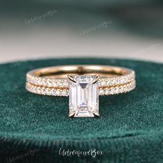 an emerald colored diamond engagement ring set on top of a green velvet box