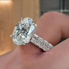 a close up of a person's hand holding a diamond ring