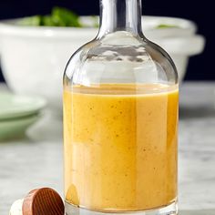 a bottle filled with liquid sitting on top of a counter next to a wooden spoon