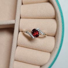 a close up of a ring with a red stone in it on a cushioned surface