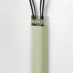 three black and white wires are in a green tube on the wall, with one wire sticking out of it