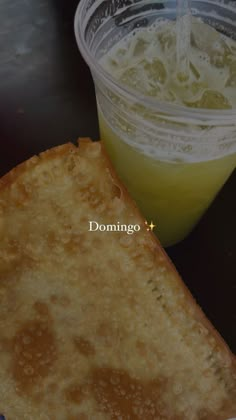 a piece of bread next to a cup of juice