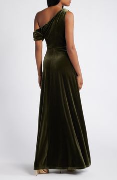 the back of a woman wearing a dark green velvet gown with one shoulder and open shoulders