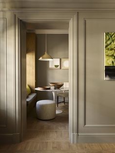 an open door leading to a dining room and living room with white walls, wood flooring and furniture