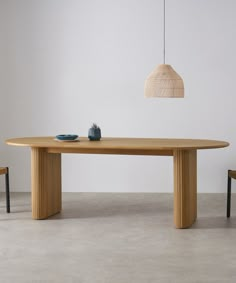 a wooden table with two chairs and a vase on the top, in front of a white wall