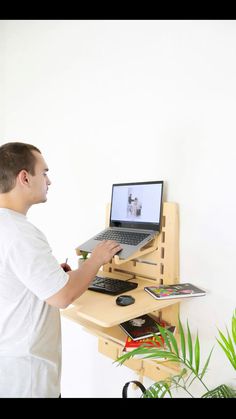 a man standing in front of a desk with a laptop computer on top of it