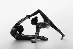 two women are doing acrobatic poses on their hands and knees, one is bent over the other