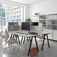 an office with multiple desks and chairs in front of large windows, all white