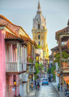 an old town street with people walking and cars driving down it