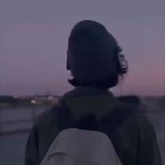 the back of a person wearing headphones looking out over a highway at sunset or dawn