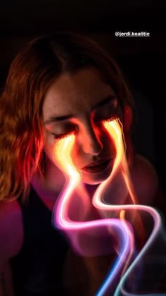 a woman with red hair is looking down at her cell phone while she's lit up