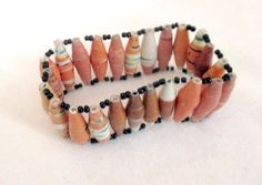 a bracelet made out of shells and beads on a white surface with beaded ends