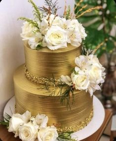 a gold wedding cake with white flowers on top