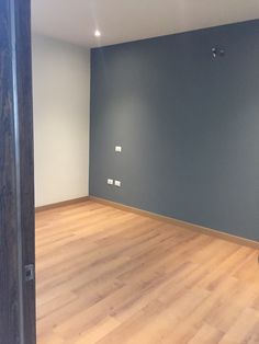 an empty room with hard wood floors and blue walls