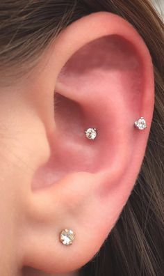 a woman's ear with three small diamond studs on the top of it